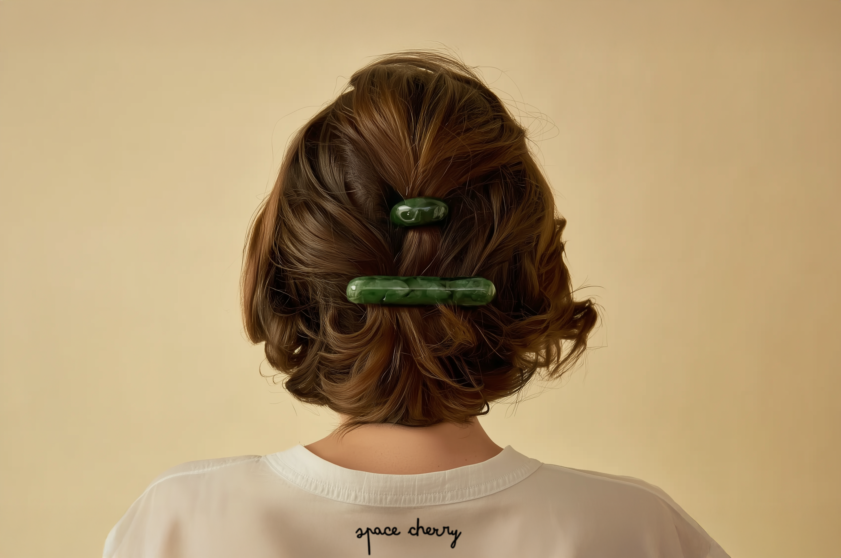 Person with styled hair featuring green hair clips on a beige background. The woman is wearing a space cherry branded tshirt.